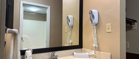 A bathroom with a sink, a mirror, a hairdryer, and a towel rack.