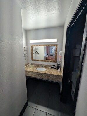 A hotel bathroom with a white sink, a mirror with a gold frame, and a towel rack. - Americas Best Value Inn Sacramento Old Town (Sacramento)