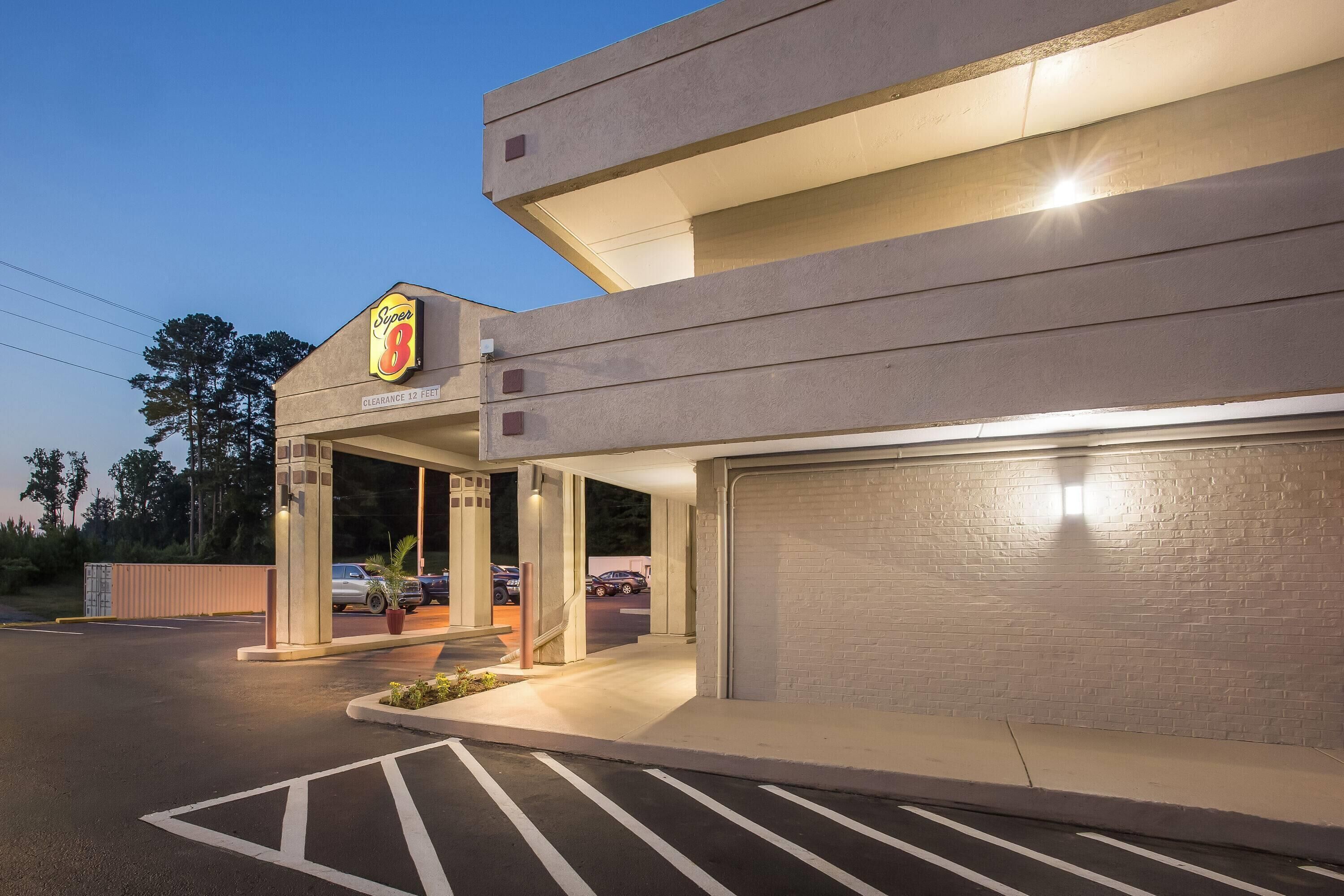 Un hotel Super 8 con un letrero visible, un estacionamiento y un muro de ladrillo.