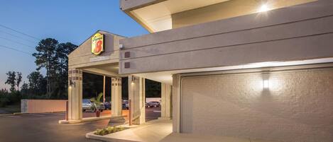 Un hotel Super 8 con un letrero visible, un estacionamiento y un muro de ladrillo.