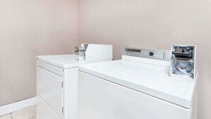 Un espace buanderie compact comprenant un lave-linge et un sèche-linge à chargement frontal, une petite planche à repasser et un fer à vapeur intégré.