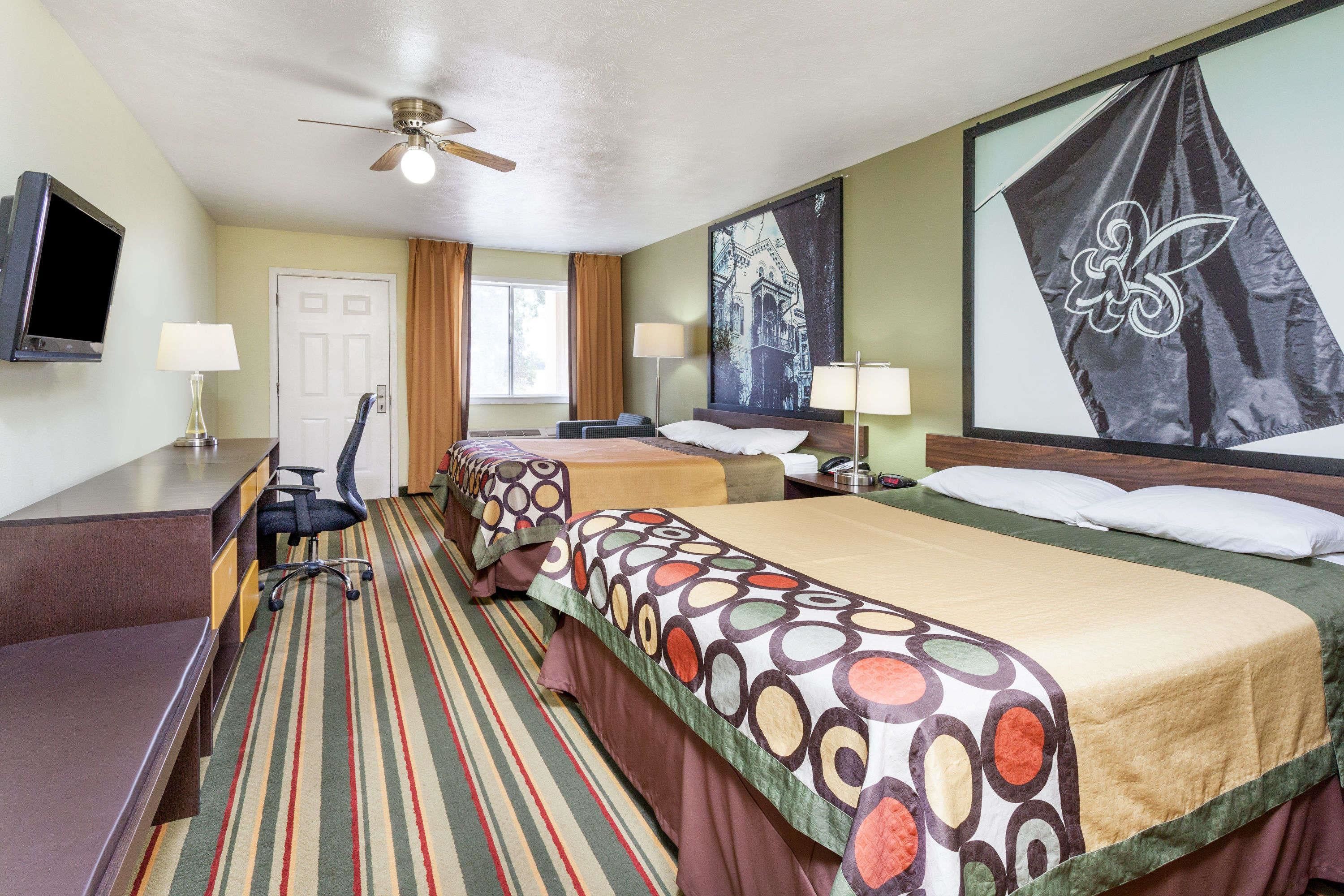 A hotel room with a bed, desk, chair, and a television.