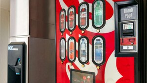 Un distributeur automatique de boissons de la marque Coca-Cola, proposant un large choix de boissons et doté d’une interface de paiement.