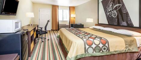 A hotel room with a bed, a desk, a chair, a TV, and a ceiling fan.