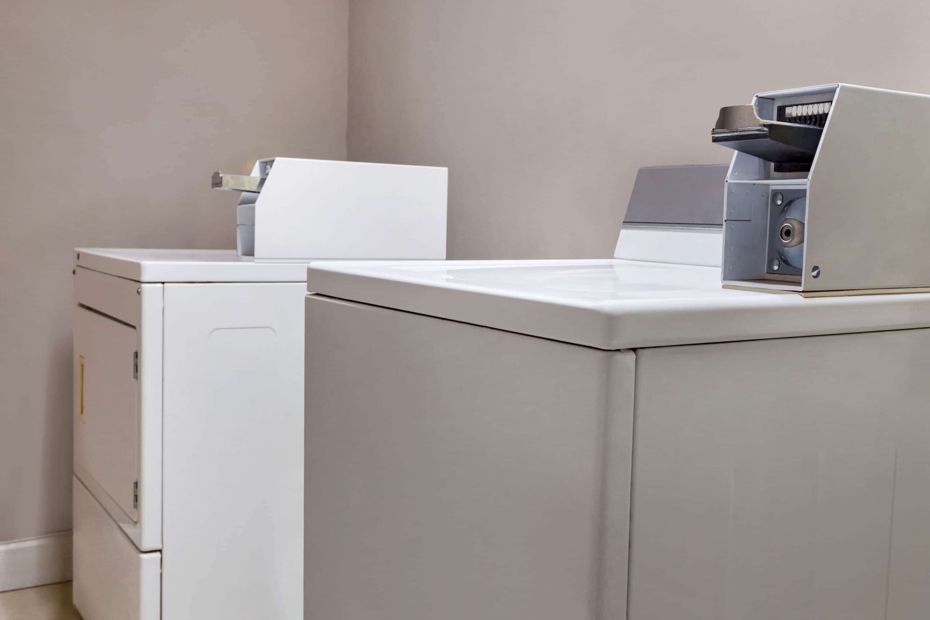 Une buanderie équipée de deux machines à laver blanches et d’un sèche-linge.
