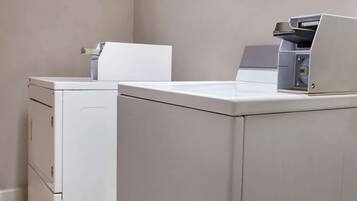Une buanderie équipée de deux machines à laver blanches et d’un sèche-linge.