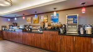 A hotel breakfast area with wooden cabinets, a coffee station, and various food items displayed.