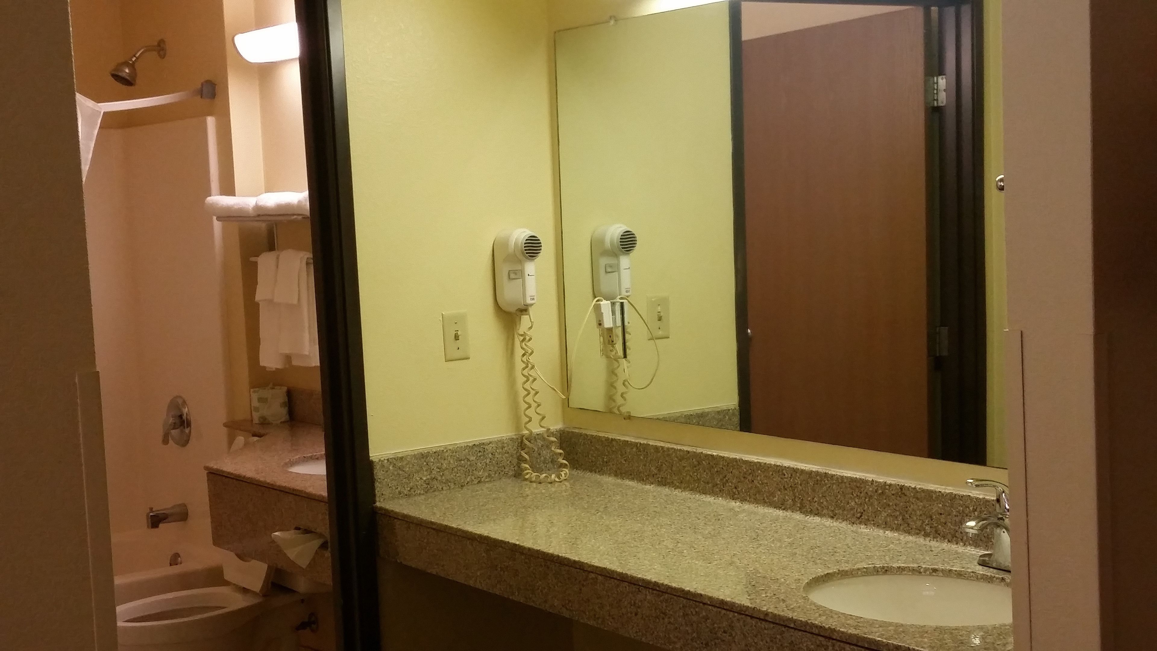 Une salle de bain équipée d’un lavabo, d’un miroir, d’un porte-serviettes et de sèche-cheveux.