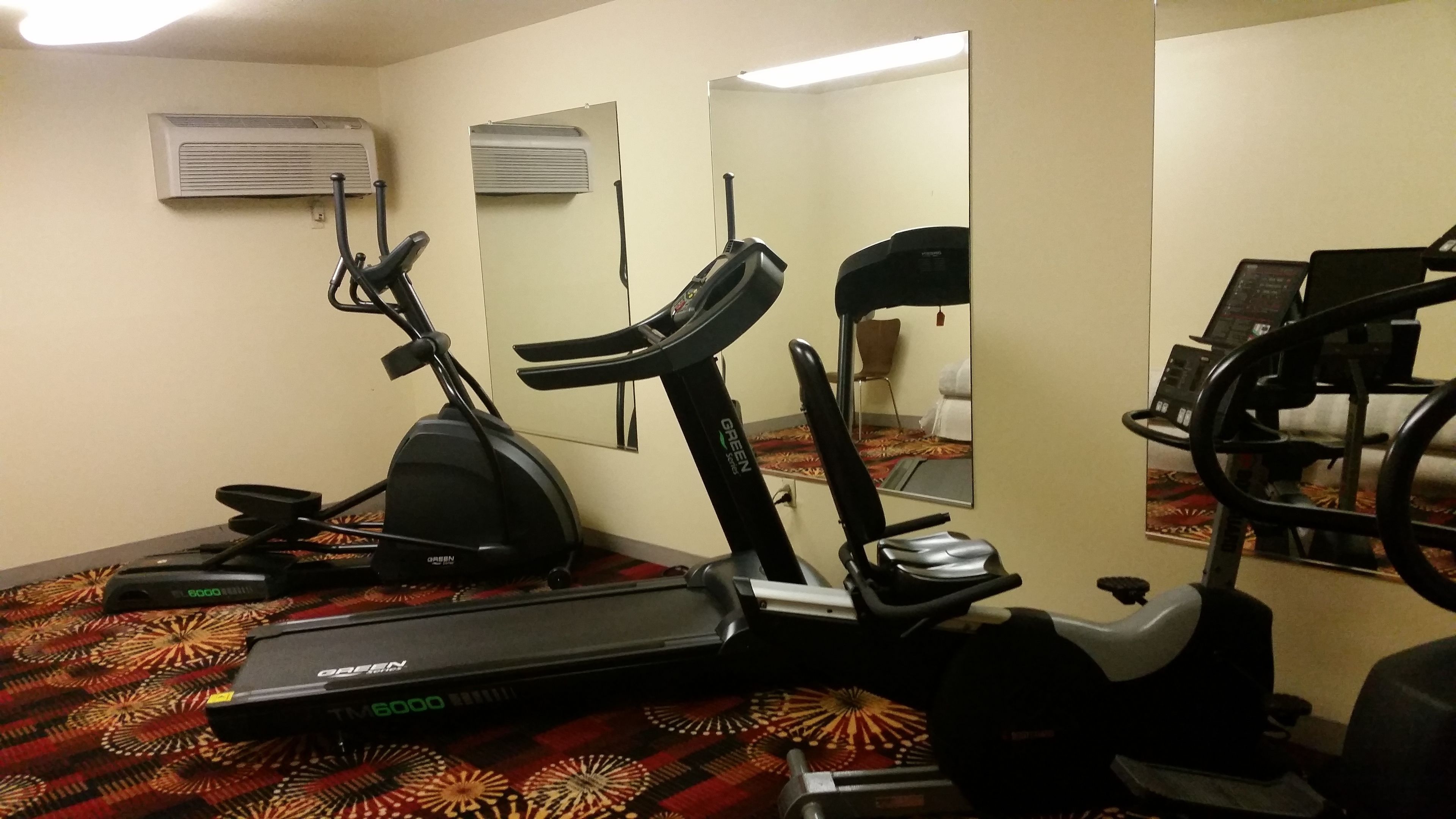 Un gimnasio con cinta de correr, elíptica y bicicleta estática.