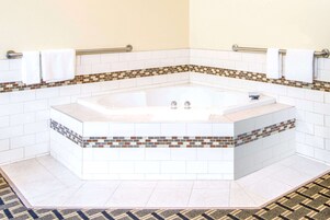 Un baño moderno con una bañera independiente, paredes de azulejos blancos y un detalle decorativo de mosaicos.