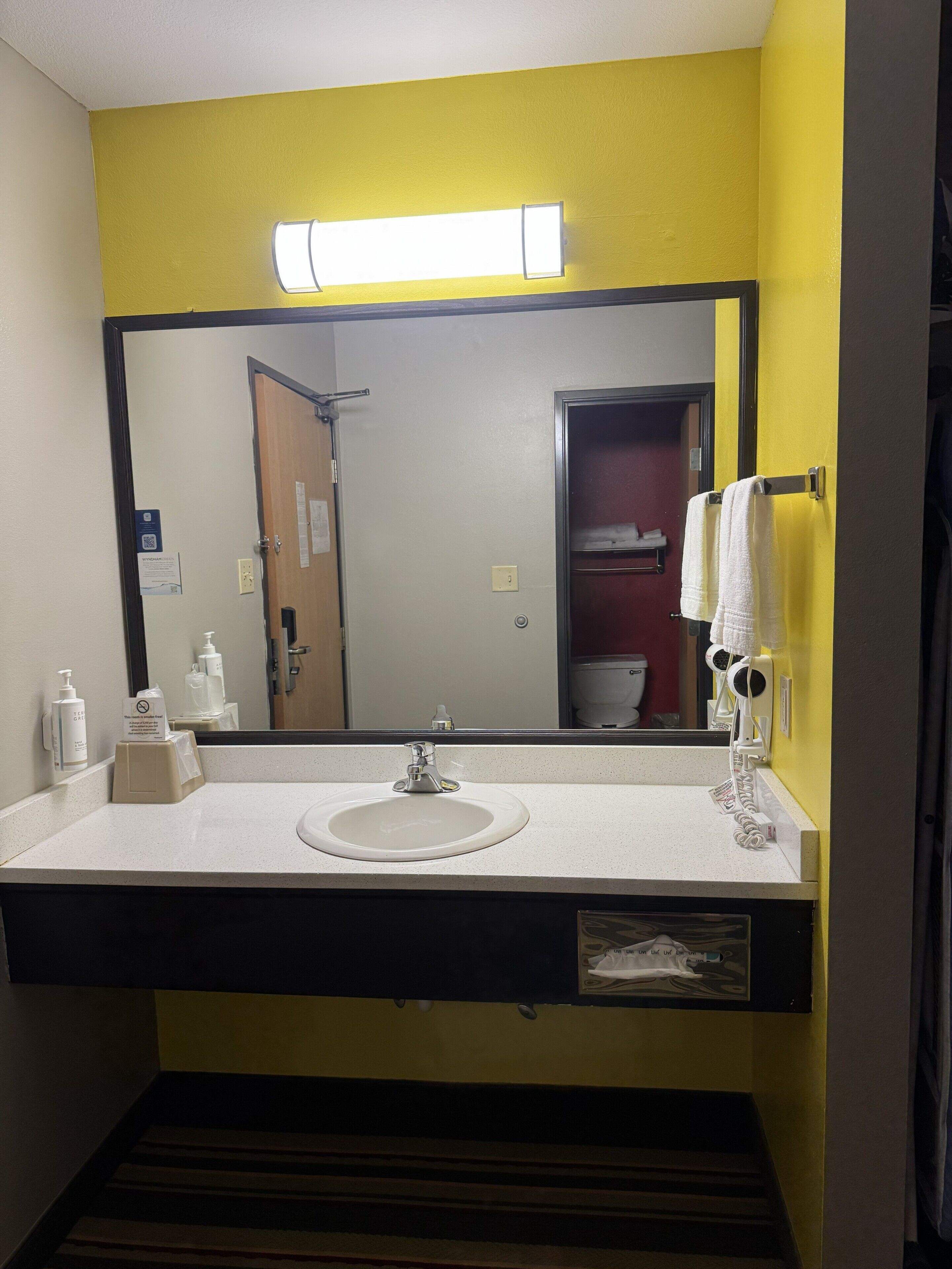 A bathroom with a white sink, a mirror, and a yellow wall.