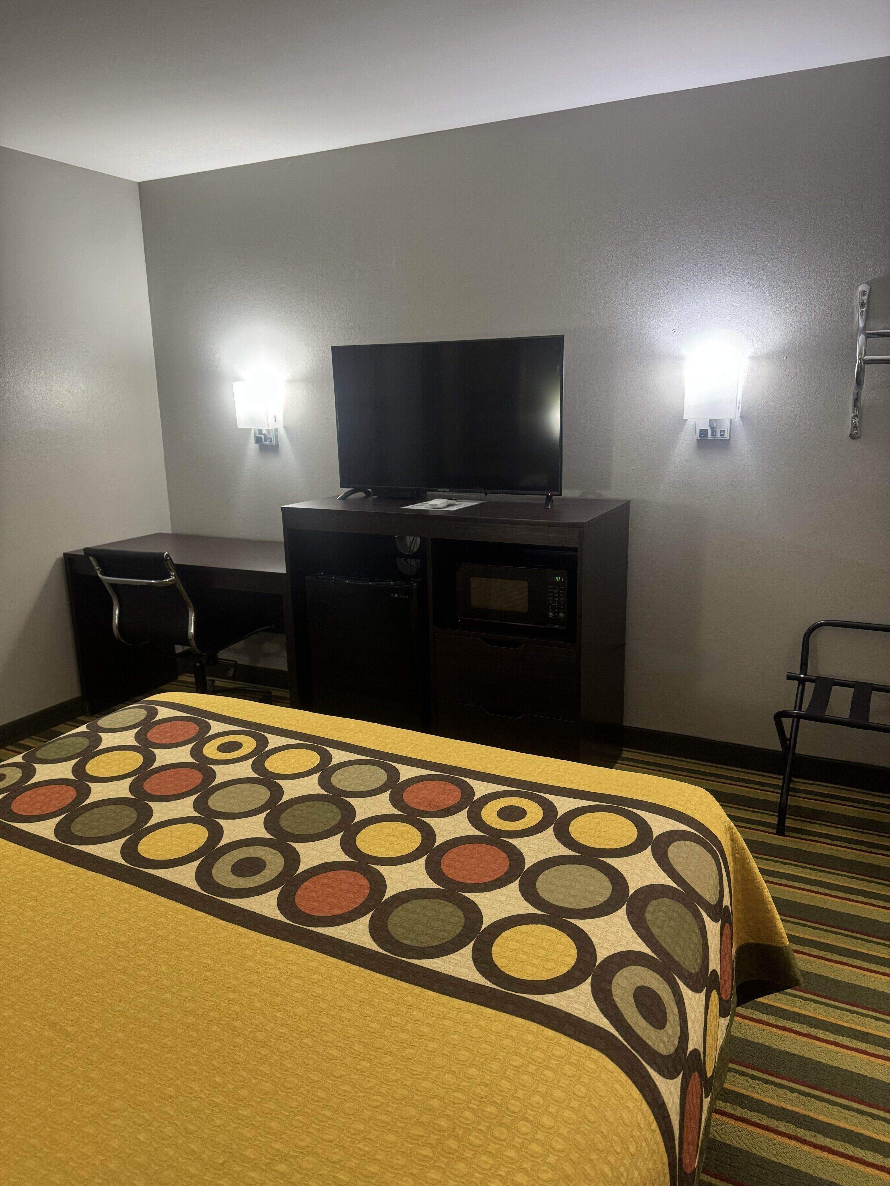 Une chambre d’hôtel équipée d’un lit, d’un bureau, d’une télévision et d’un four à micro-ondes.