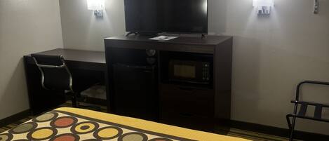 Een hotelkamer met een bed, bureau, televisie en een magnetron.