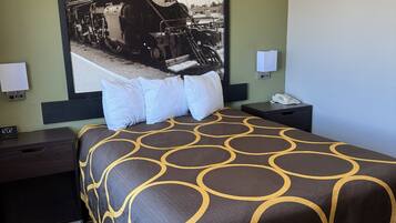 Une chambre d’hôtel avec un grand lit, deux tables de chevet, une horloge et un téléphone fixé au mur.