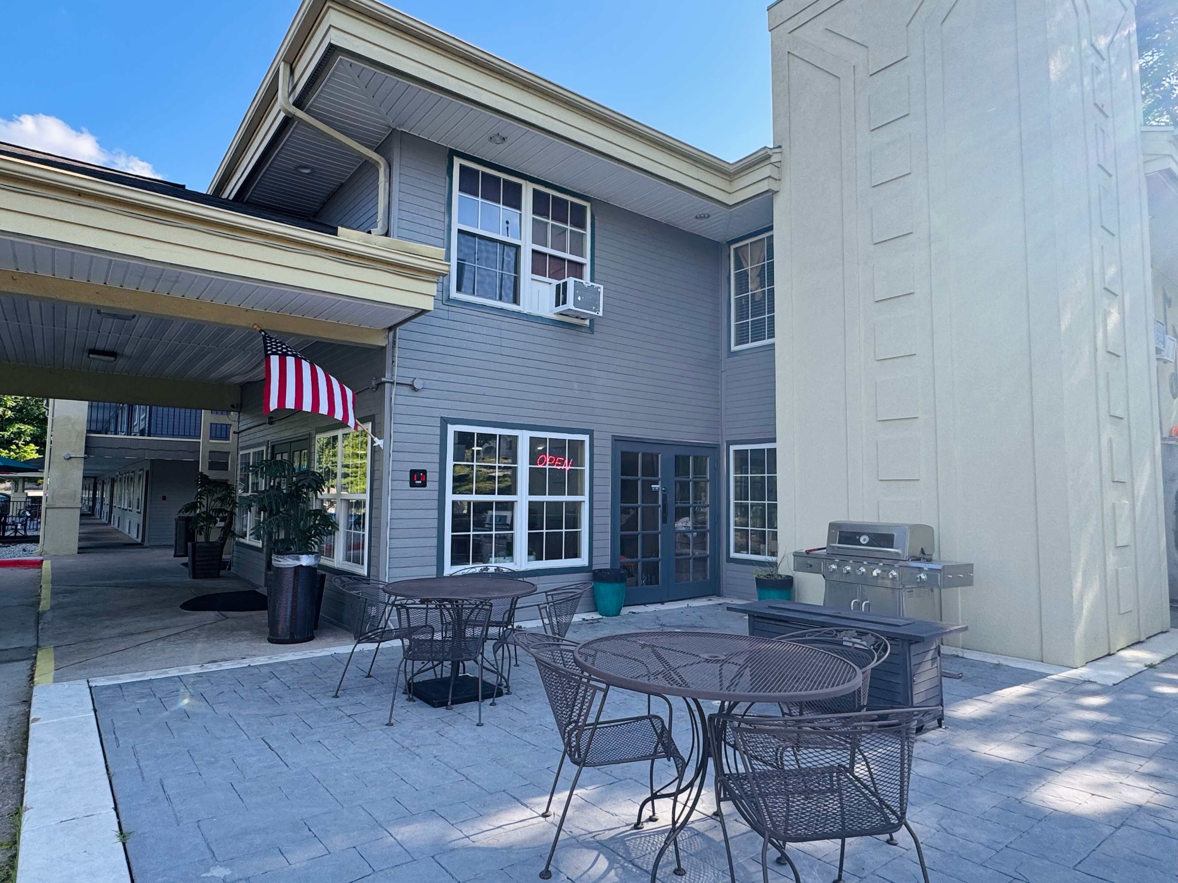 Un patio con mobiliario exterior y una parrilla.