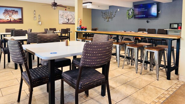 A restaurant with multiple tables and chairs, ceiling fans, a flat-screen TV, and a microwave. - Wander Inn (Branson)