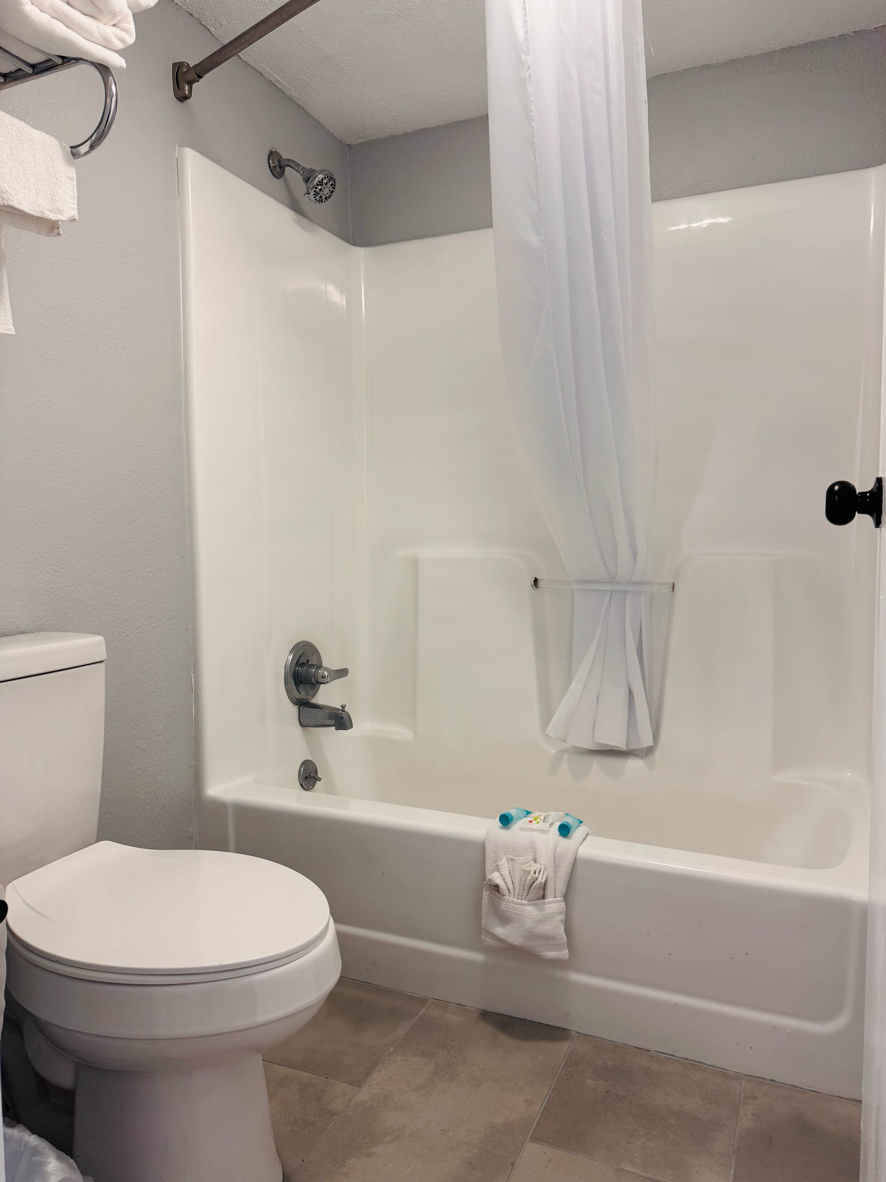 Et badeværelse med et hvidt badekar, toilet og en bruseforhæng.