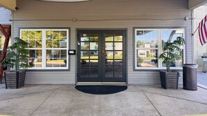 A building entrance with a dark door, two windows, and a black mat. - Wander Inn (Branson)