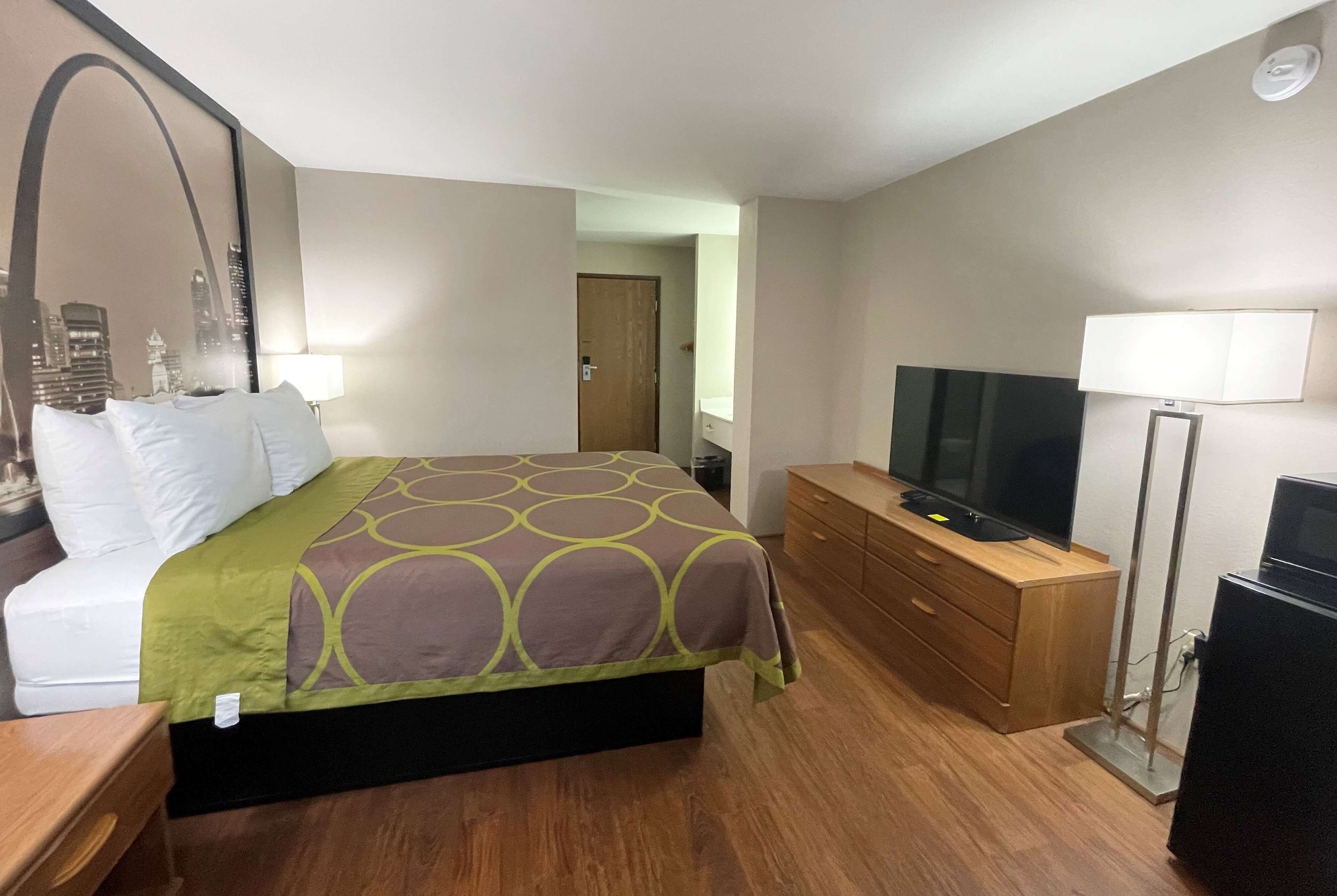 Una habitación de hotel con cama, televisión, cómoda y lámpara.