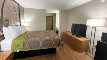 Una habitación de hotel con cama, televisión, cómoda y lámpara.