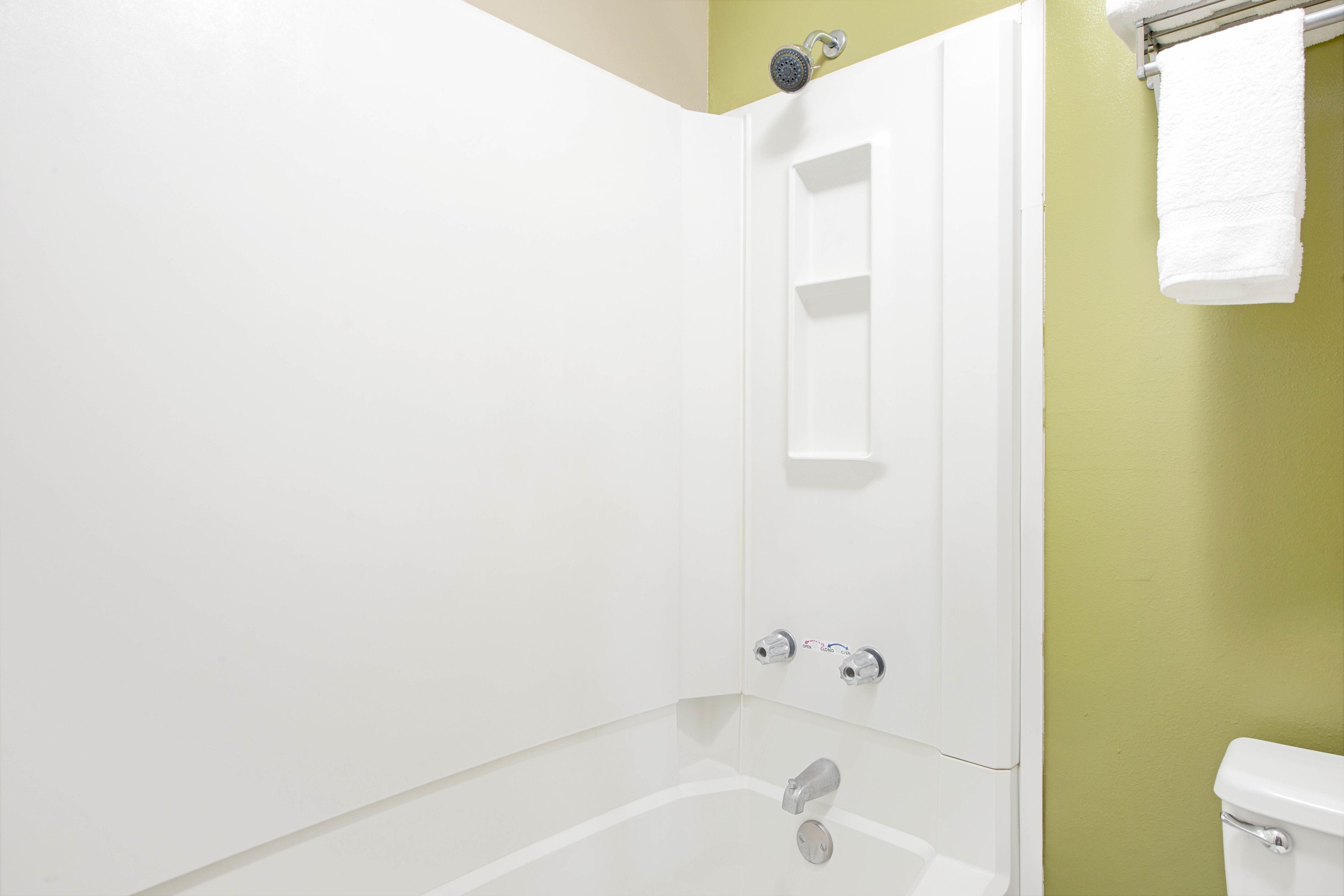 Een badkamer met een witte badkuip, een douche en een toilet.