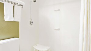 Een badkamer met een douche, een klein wit krukje en een handdoekhouder.