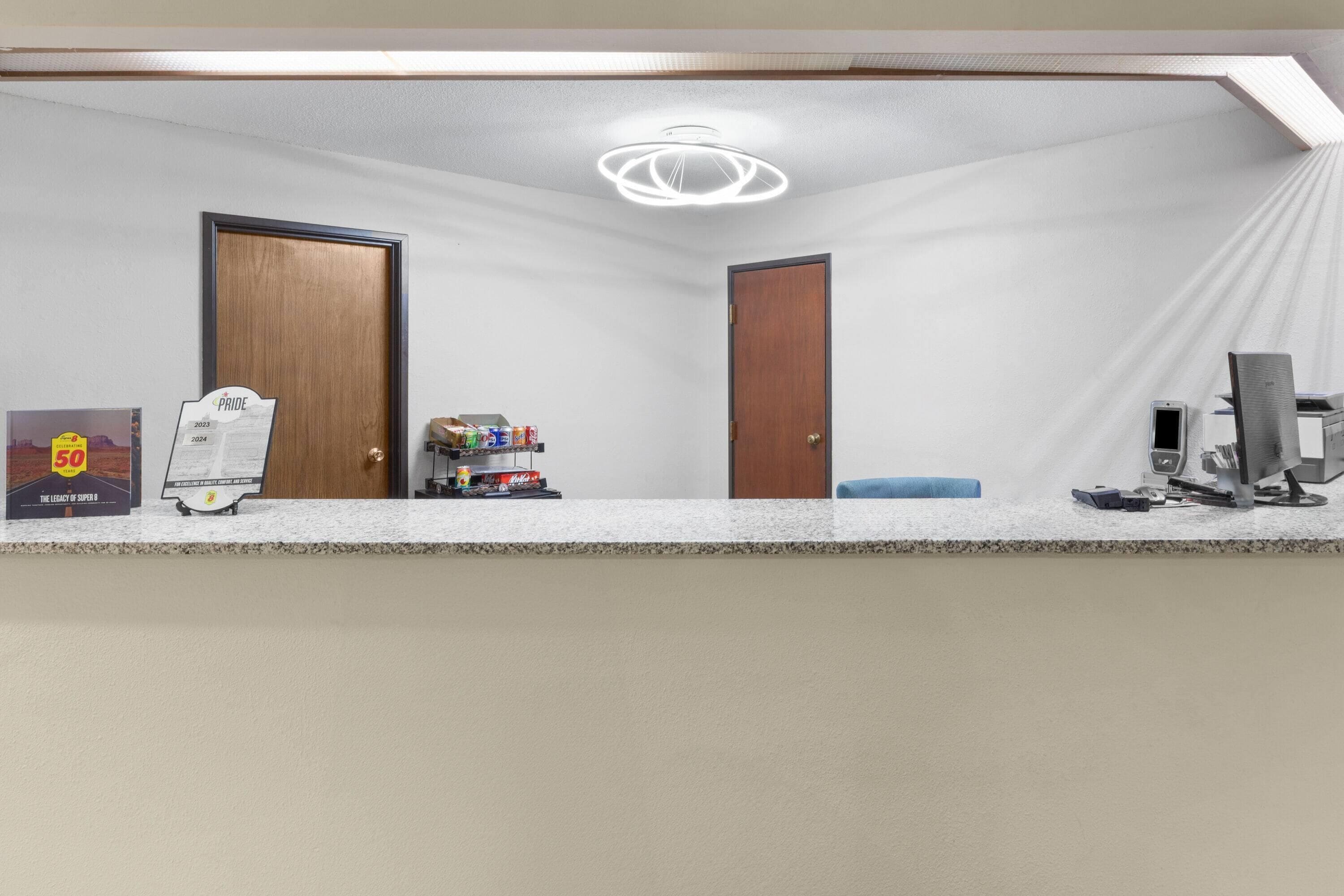 A reception area with a counter, framed awards, a door, and a ceiling light fixture.