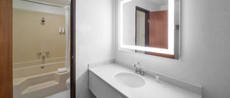 Un baño moderno con lavamanos blanco, espejo y bañera.