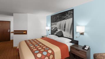 Una habitación de hotel con cama, mesita de noche, teléfono y lámpara de pared.