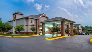 Ein Hotel mit modernem Design, das einen großen Eingangsbereich, eine überdachte Wartezone und einen Parkplatz bietet.