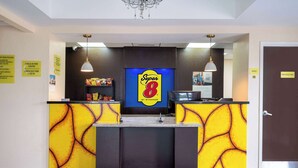 Ein Empfangsbereich mit einem Super 8 Schild, einer Schilder mit Ein- und Auscheckzeiten sowie einer Tür mit der Aufschrift 'Office'.