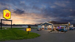 A Super 8 motel with a large sign, a parking lot, and a building with a sloped roof. - Super 8 by Wyndham Newcomerstown (Newcomerstown)