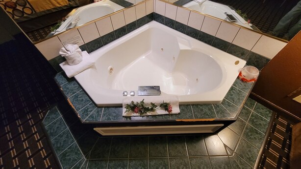 A modern bathroom with a large bathtub, a mirror, and a shower area. - Super 8 by Wyndham Newcomerstown (Newcomerstown)