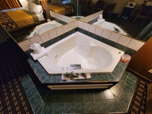 A modern bathroom with a large bathtub, a mirror, and a shower area.