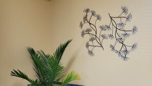 A potted plant in a blue pot, a wall with a decorative metal tree, and a tiled floor with a blue stripe. - Super 8 by Wyndham Newcomerstown (Newcomerstown)