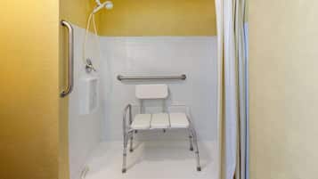 Eine barrierefreie Dusche mit Haltegriff, Duschkopf und Sitzgelegenheit.
