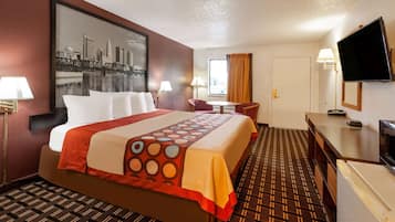 Une chambre d’hôtel avec un grand lit, un bureau, une chaise, une télévision et une fenêtre avec des rideaux.