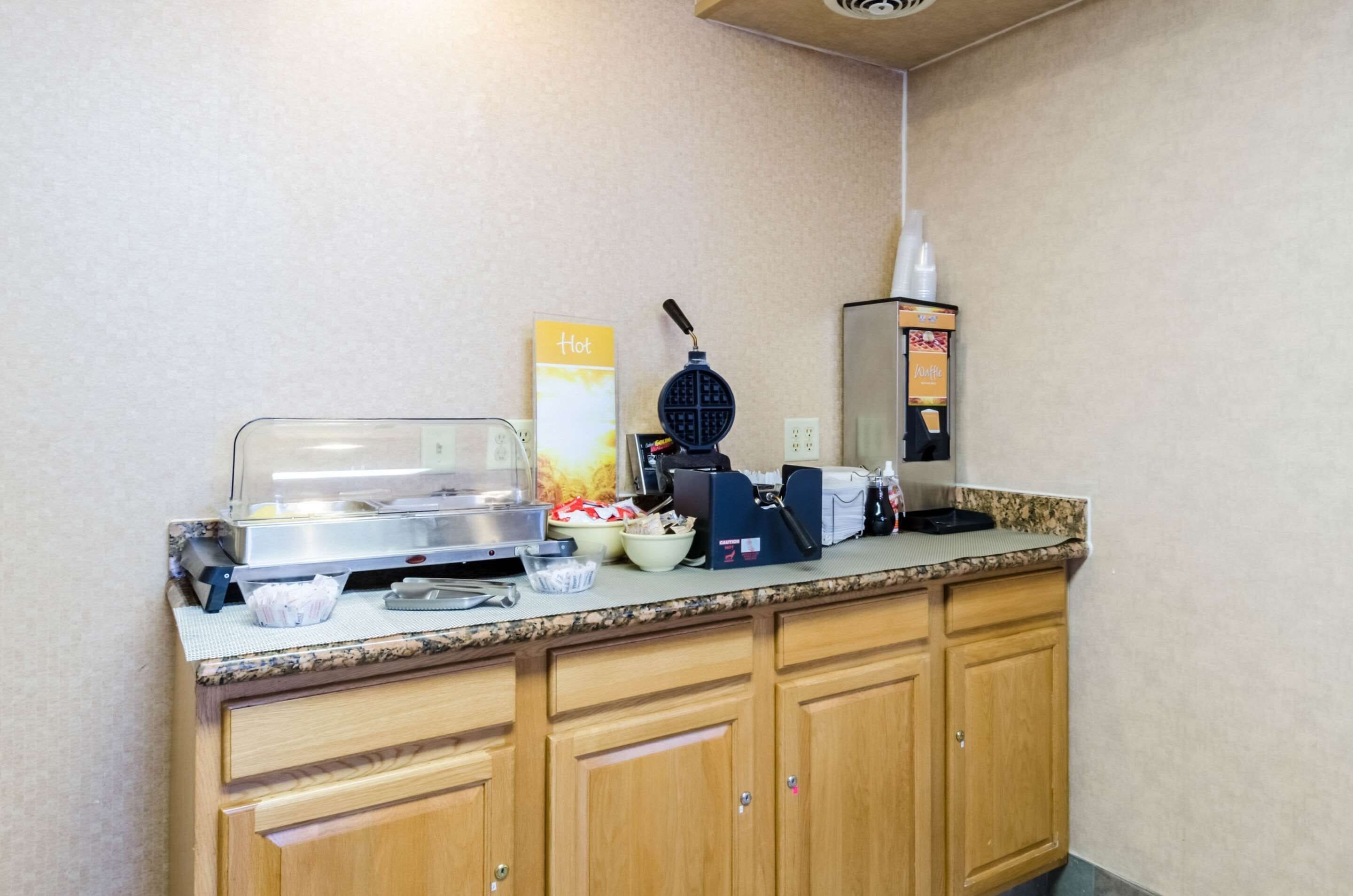 Una kitchenette equipada con una máquina para hacer gofres, una cafetera y un dispensador de bebidas calientes.