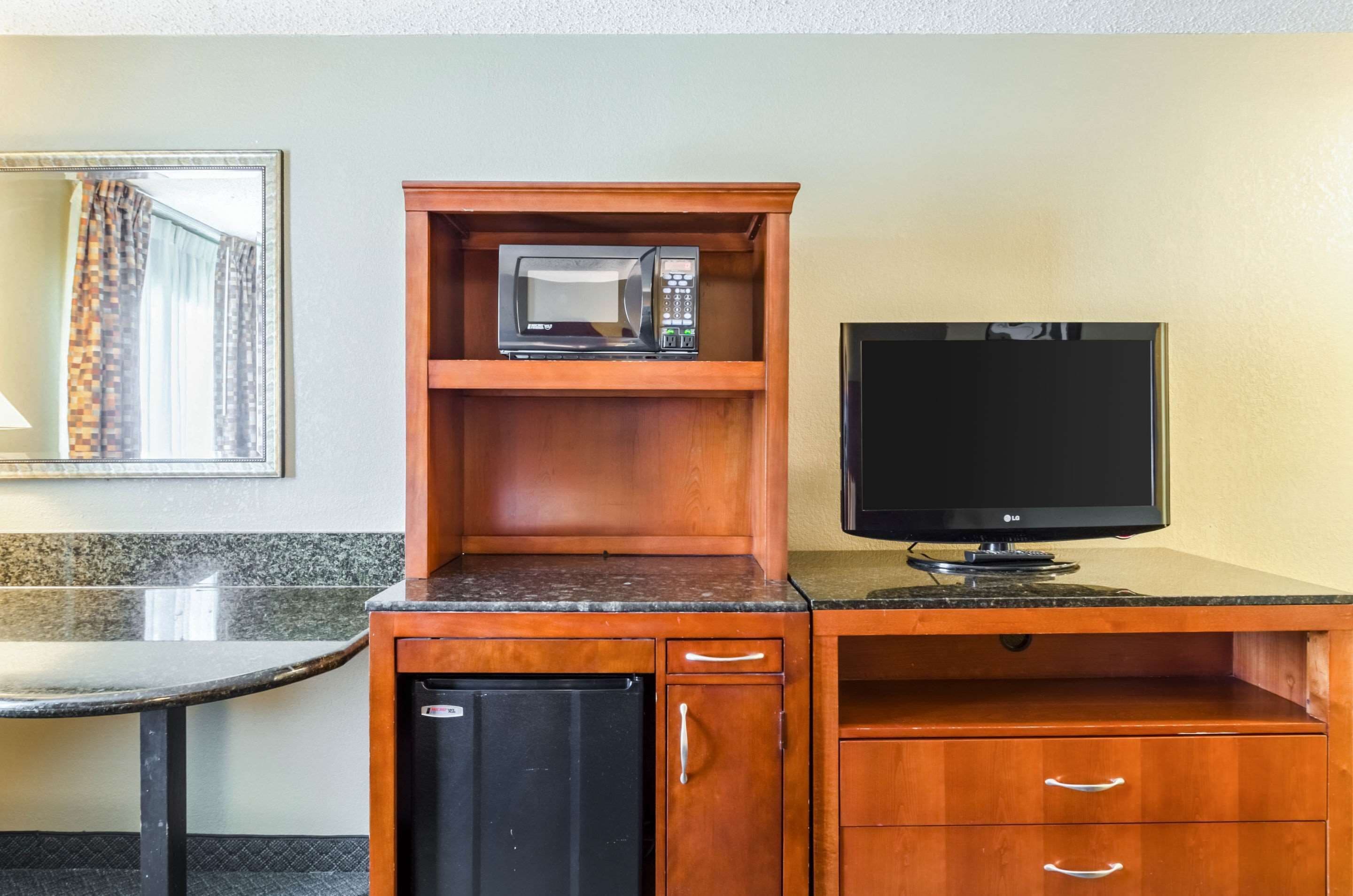 Una kitchenette compacta con microondas, televisión y un refrigerador pequeño.