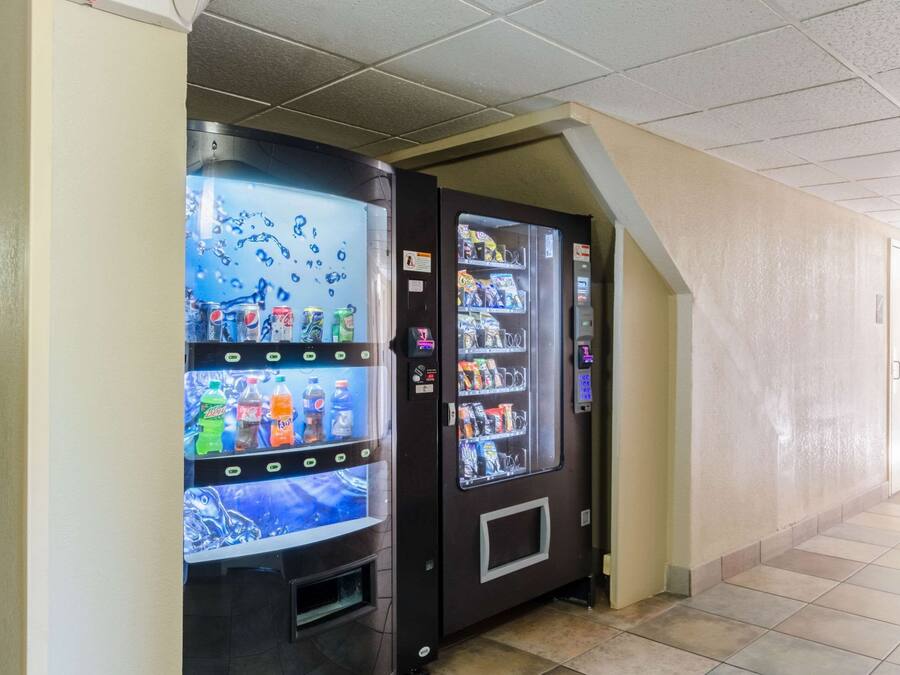 Two vending machines in a hallway with tiled flooring and a sloped ceiling.