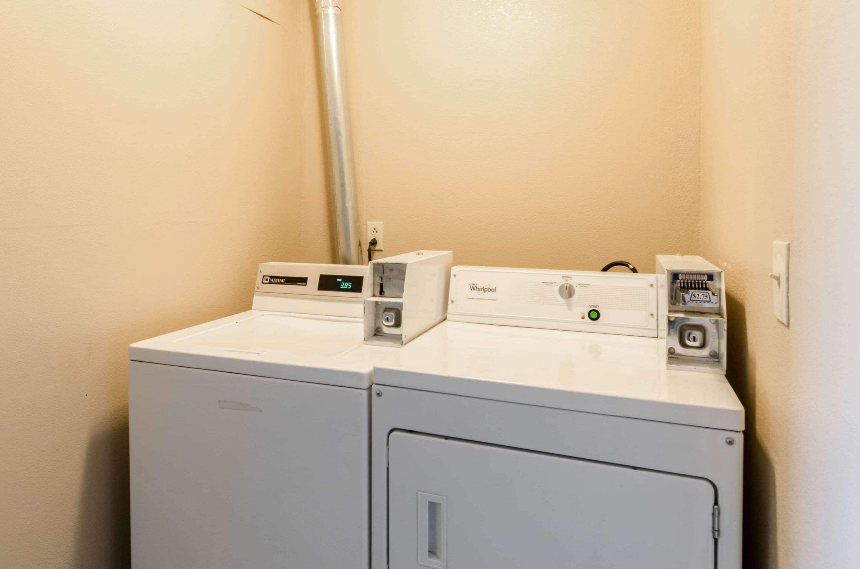 A laundry area with two stacked washers and dryers, a visible power outlet, and a metal vent pipe.