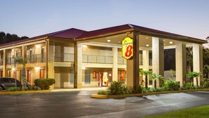 A hotel with a red roof, multiple balconies, and a prominent 'Super 8' sign. - Super 8 by Wyndham Defuniak Springs (De Funiak Springs)