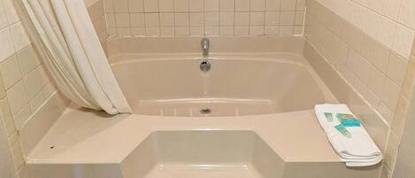 A bathroom with a bathtub, a sink, and a towel rack.