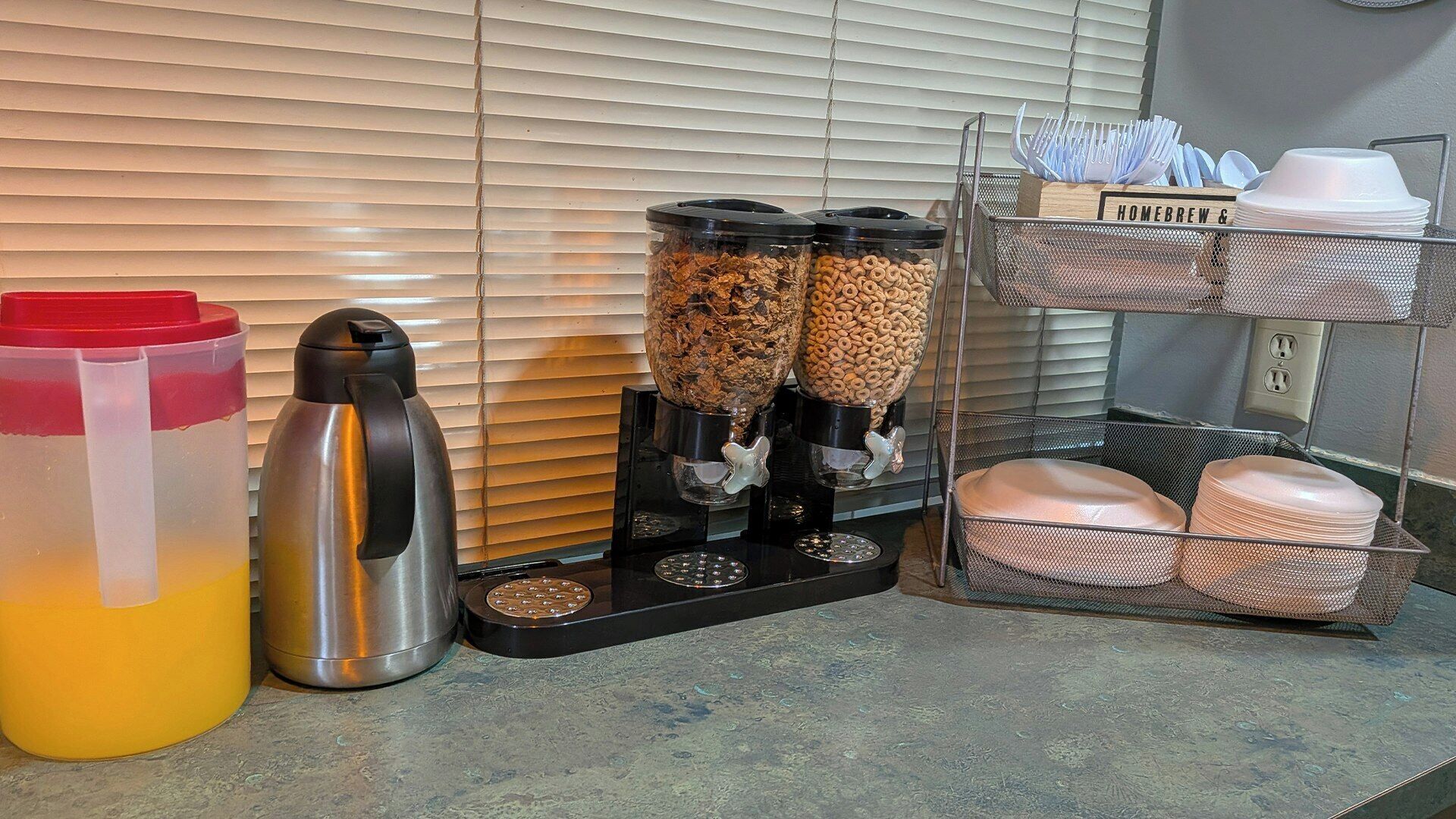 A kitchenette with a coffee maker, a water dispenser, and a dish rack.