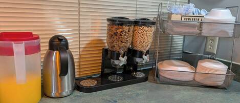 A kitchenette with a coffee maker, a water dispenser, and a dish rack.