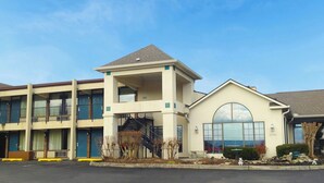 A multi-story hotel with a central staircase, a covered outdoor seating area, and a large arched window. - Inn of Loudon (Loudon)