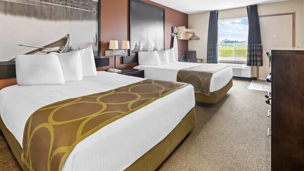 Ein Hotelzimmer mit zwei Betten, einem großen Fenster und Blick ins Freie.