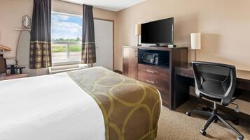 A hotel room with a bed, a desk with a TV, a chair, and a window with curtains.