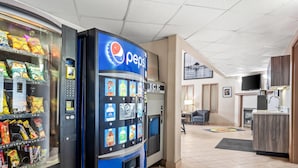 Ein Verkaufsautomatenbereich mit Pepsi und anderen Snacks, ein Wasserspender und ein Empfangstresen in der Hotelhalle.