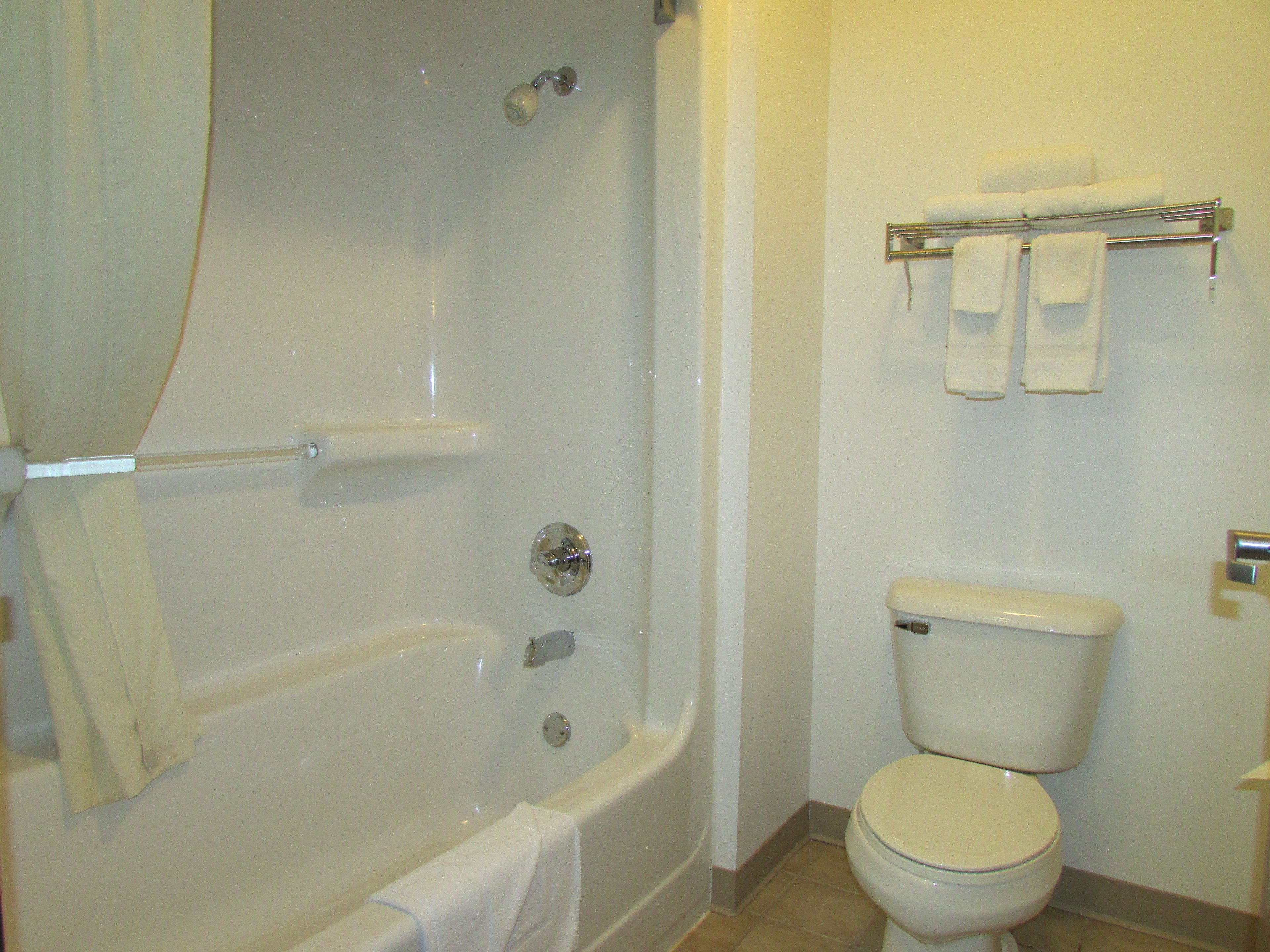 A bathroom with a bathtub, toilet, and a towel rack with towels.